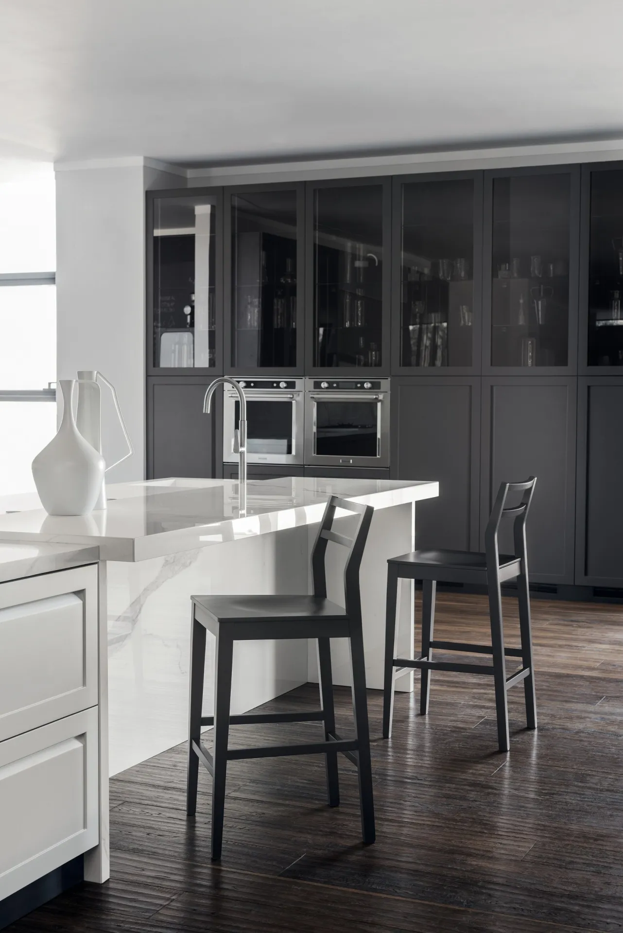Sgabelli Flair Scavolini laccati scuri davanti a un'isola bianca in una cucina con colonne scure