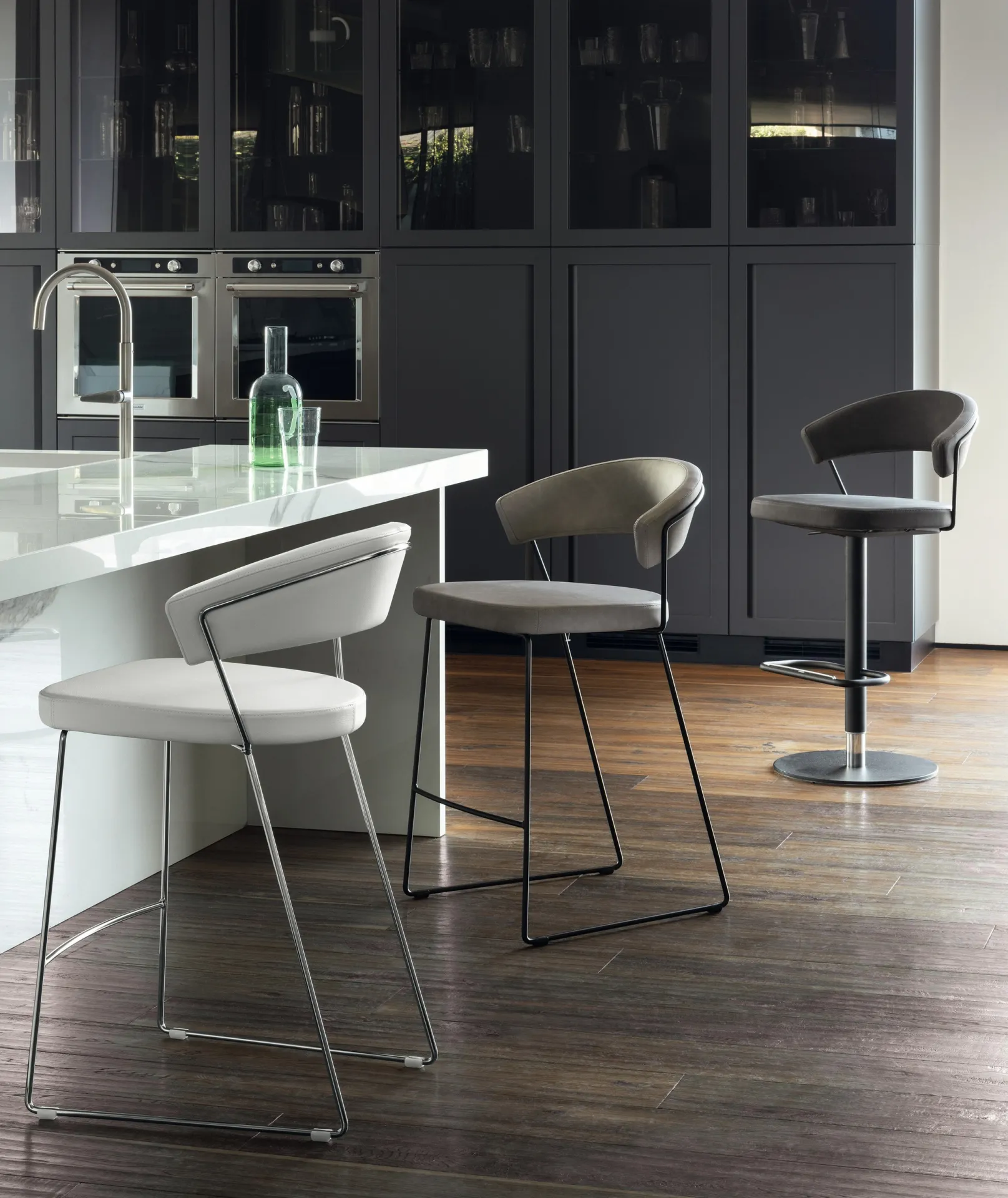 Sgabelli Great Scavolini bianchi e tortora davanti a un'isola bianca in una cucina con vetrine scure