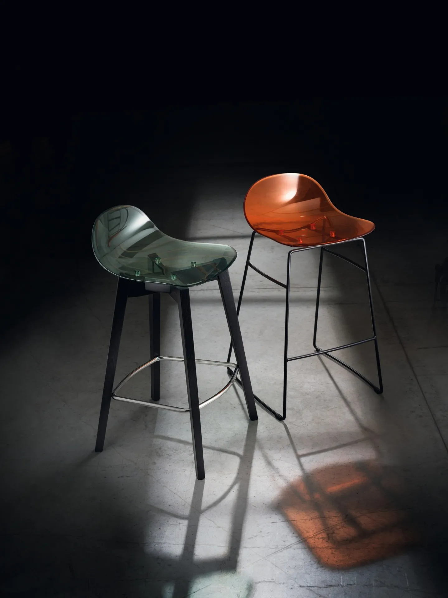 Sgabelli Hero Pop Scavolini arancio e verde trasparenti in un ambiente buio
