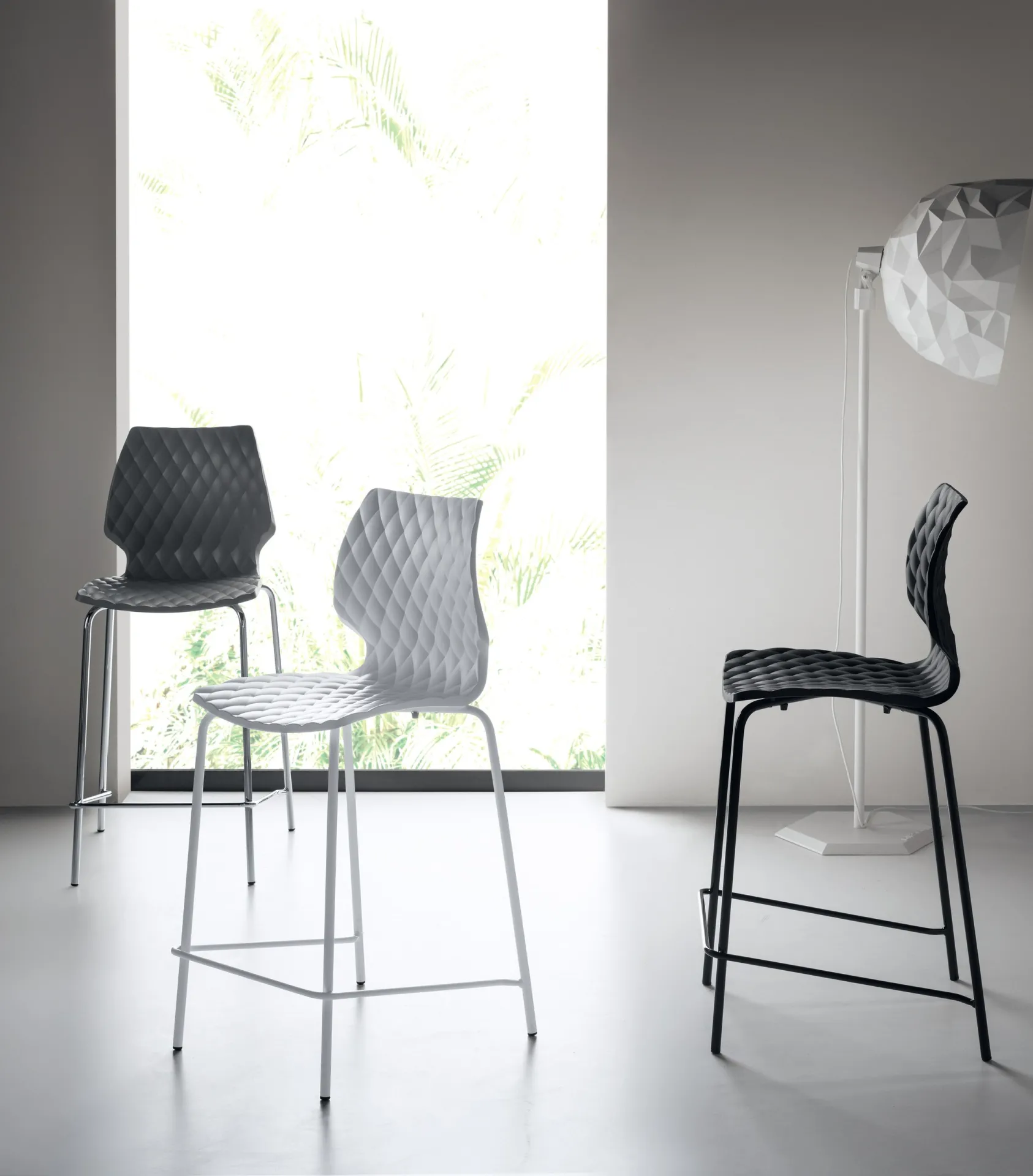 Tre sgabelli Homy Scavolini bianco, grigio e nero davanti a una vetrata luminosa
