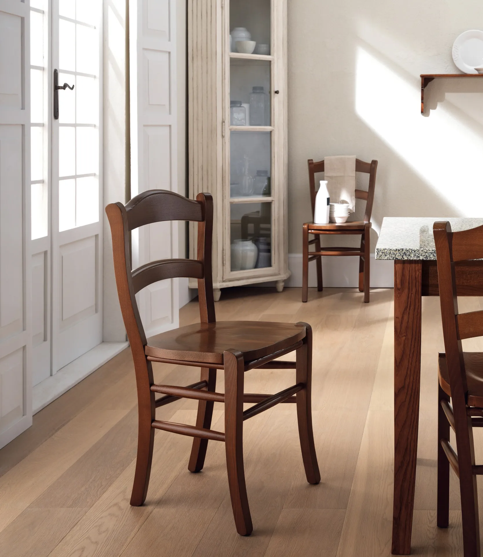 Sedie Margot Scavolini in noce in una cucina luminosa con porta finestra