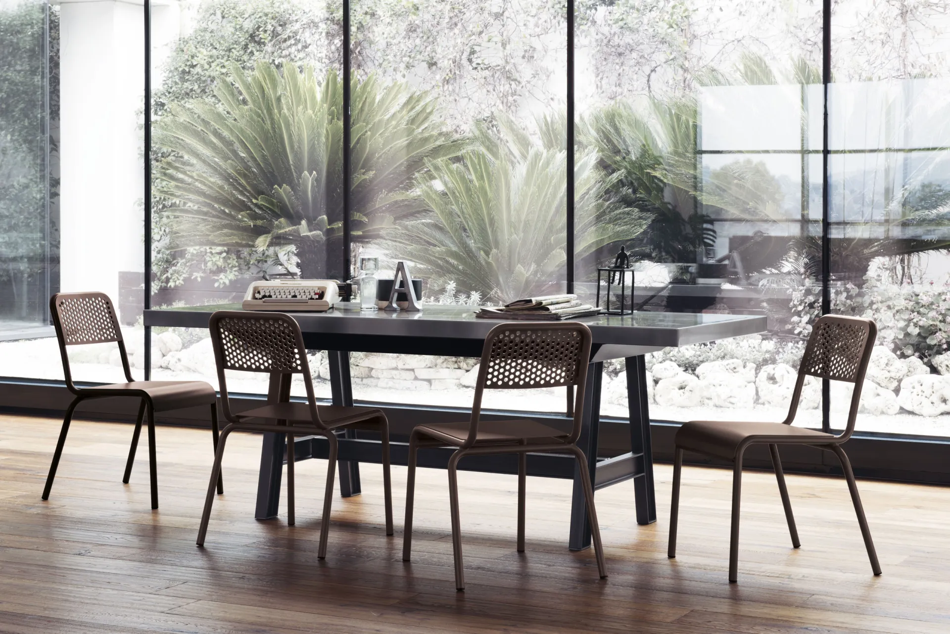 Sedie Nizza Scavolini color bronzo attorno a un tavolo davanti a una vetrata sul giardino