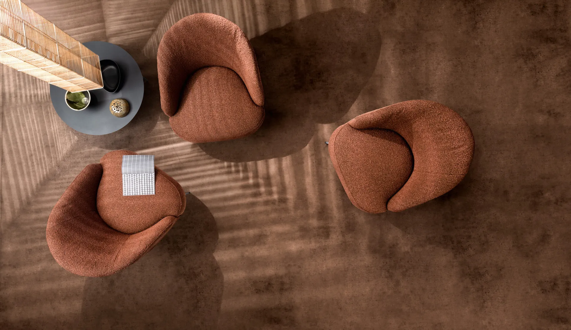 Tre poltroncine Ginko Samoa in bouclé terracotta viste dall'alto attorno a un tavolino tondo