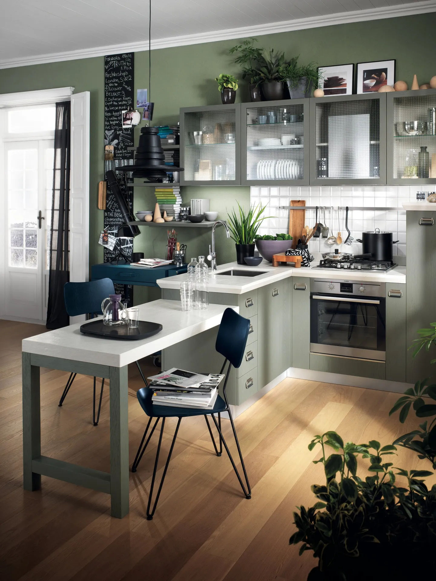 Sedie Overdyed Scavolini attorno a un tavolo in una cucina verde con piante