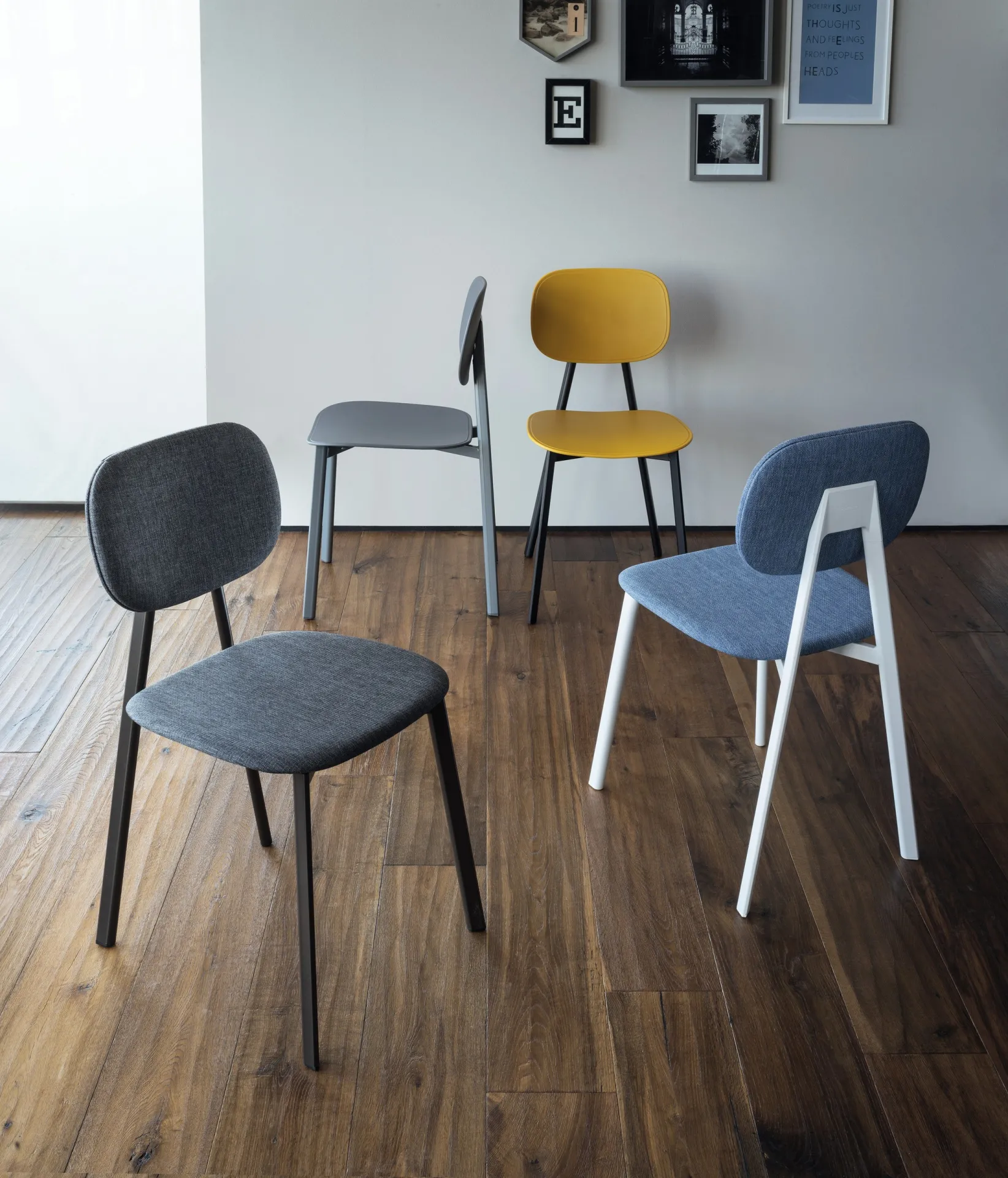 Sedie Painter Scavolini in tessuti blu, grigio e giallo su un parquet scuro