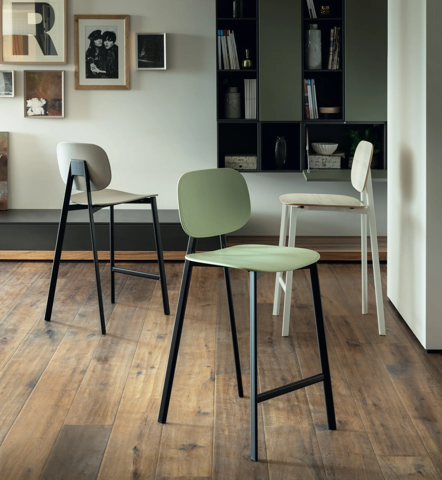 Sgabello Painter Scavolini con fondino verde accanto alle sedie della serie davanti a una libreria