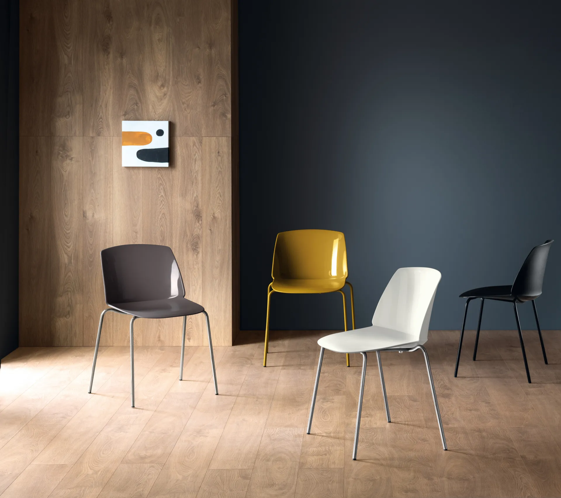 Sedie Sixties Scavolini in quattro colori su parquet davanti a una parete blu