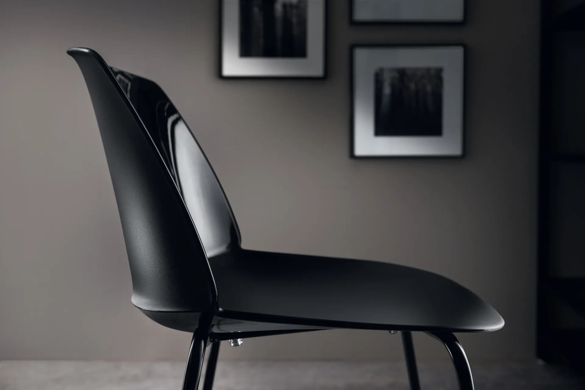 Sedia Sixties Scavolini nera lucida di profilo in una stanza con quadri