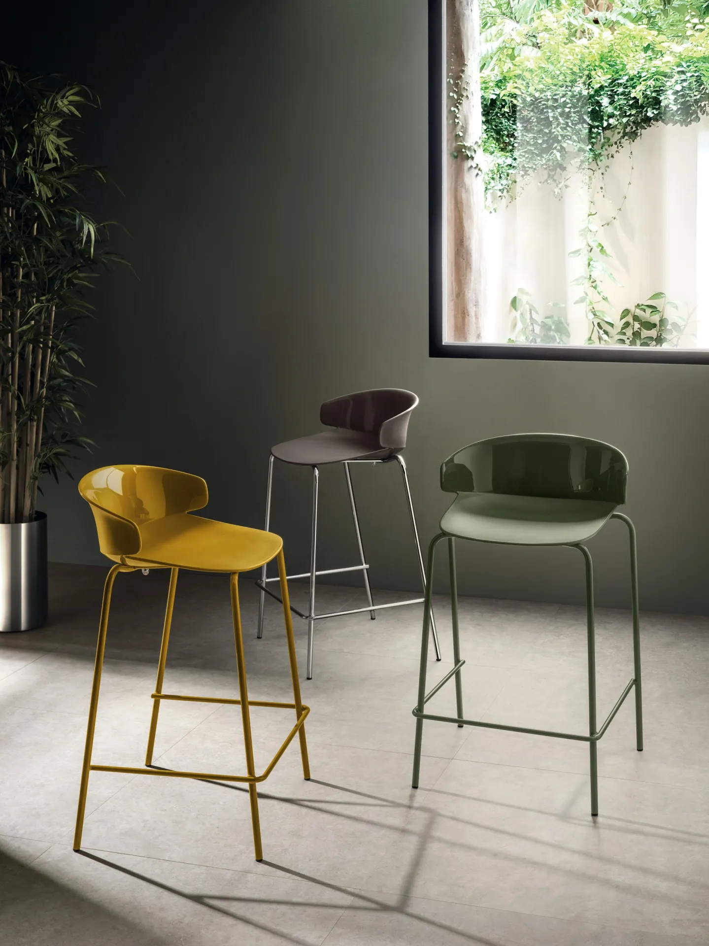 Sgabelli Sixties Scavolini giallo, tortora e verde in una stanza con parete scura
