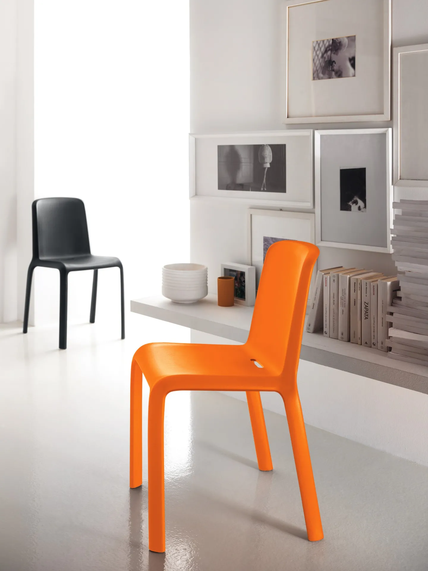 Sedie Snow 300 Scavolini arancione e nera in un ambiente bianco con quadri