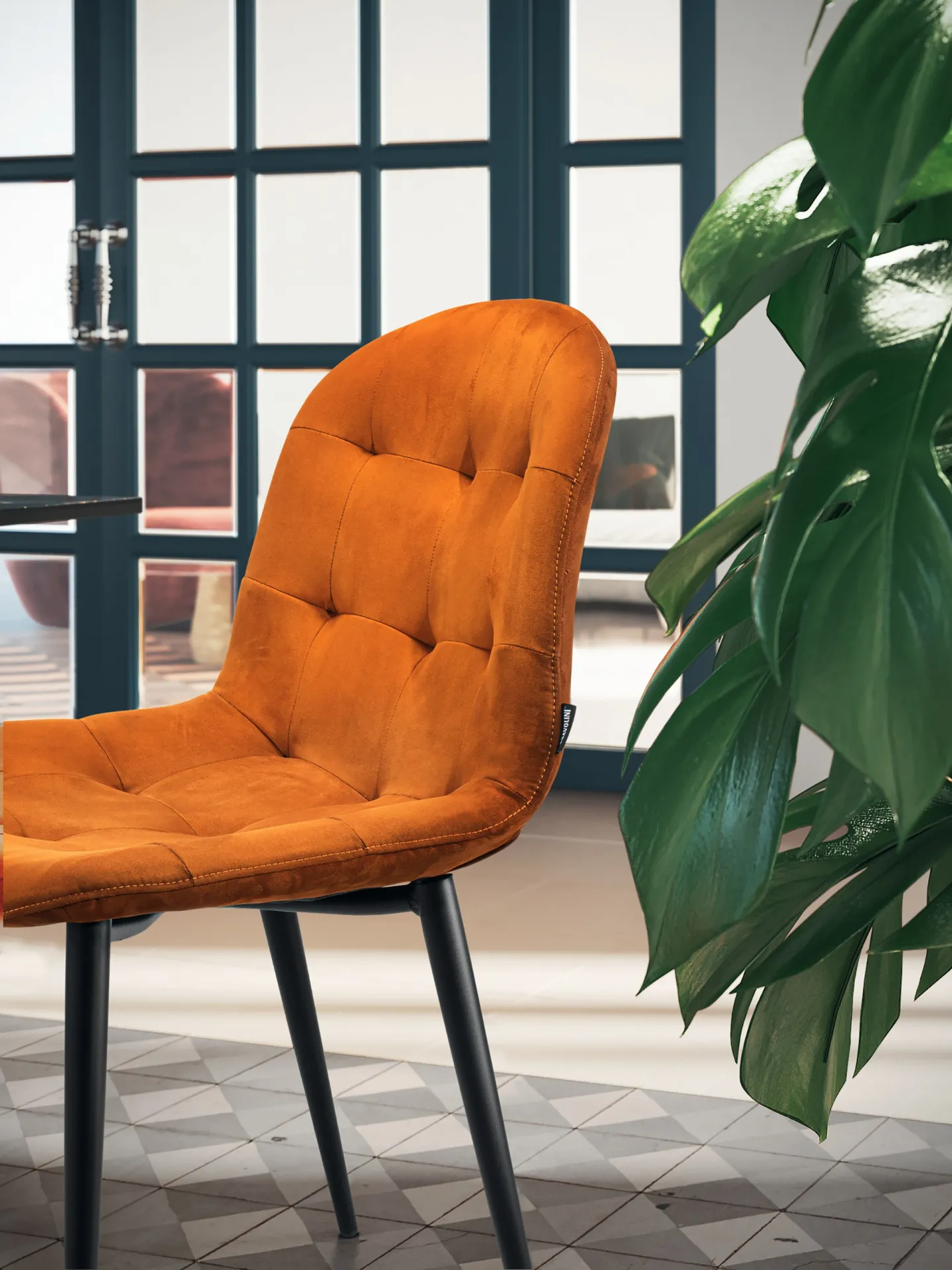 Dettaglio della trapuntatura della sedia Soft Scavolini arancio accanto a una vetrata
