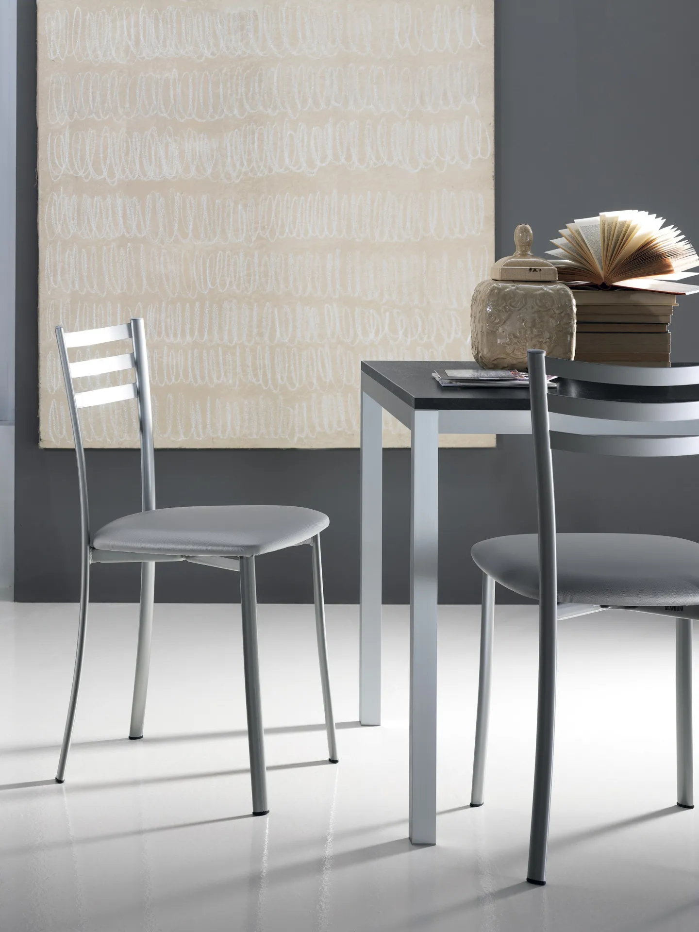 Sedie Speedy Scavolini grigio argento accanto a un tavolo in un ambiente chiaro