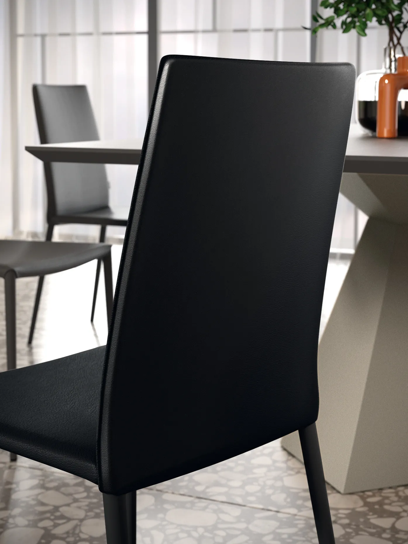 Schienale della sedia Unique Scavolini nera visto da dietro accanto al tavolo