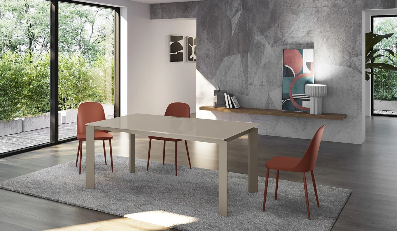 Tavolo allungabile Frame Stones con piano tortora e sedie rosse in un soggiorno con vetrate