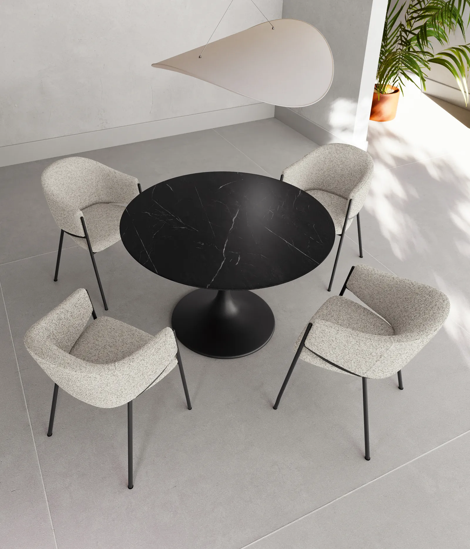 Tavolo rotondo Side Stones marmo nero con sedie chiare in un ambiente luminoso