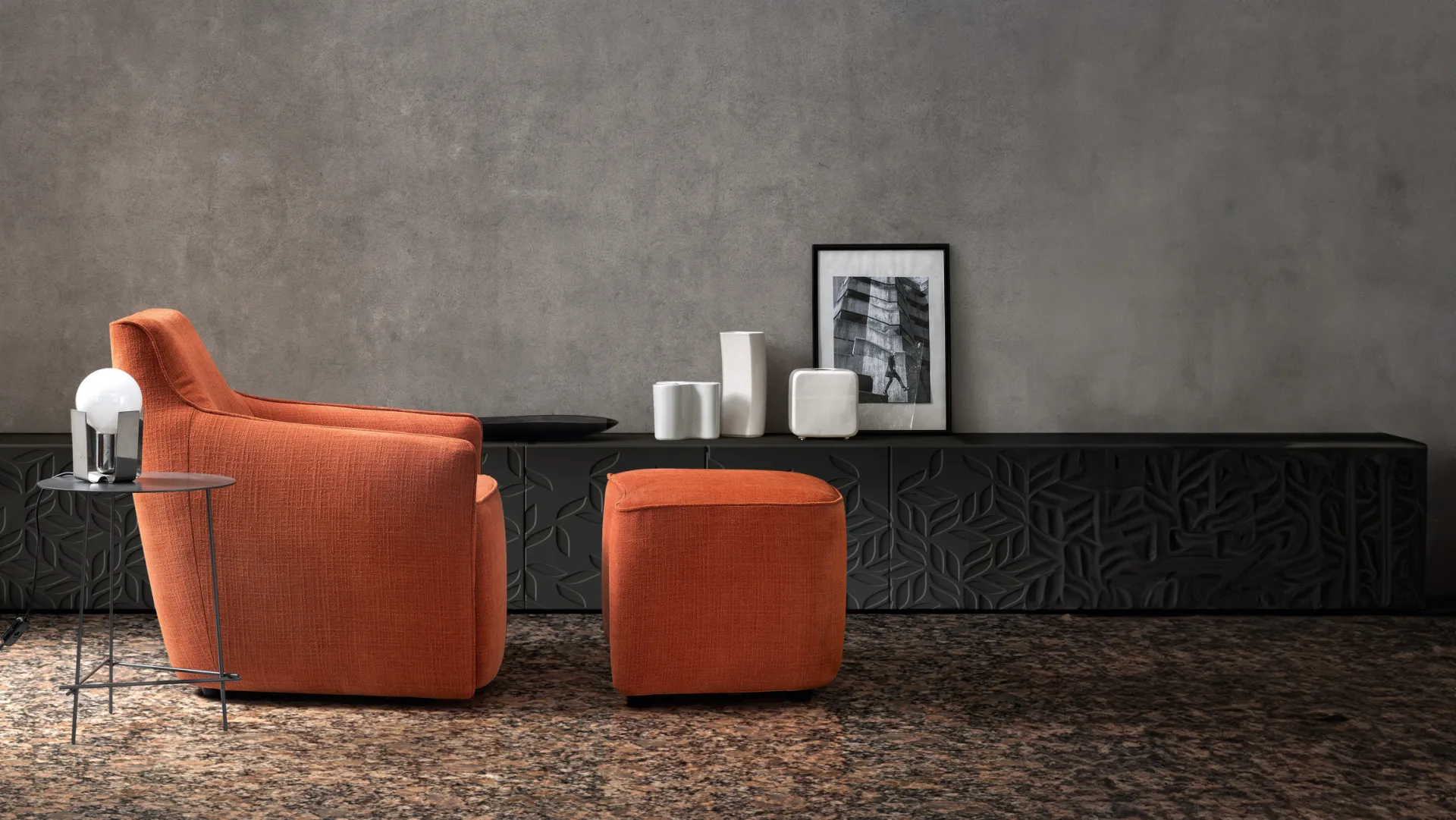 Poltrona Malik Samoa arancio con pouf coordinato davanti a una madia scura