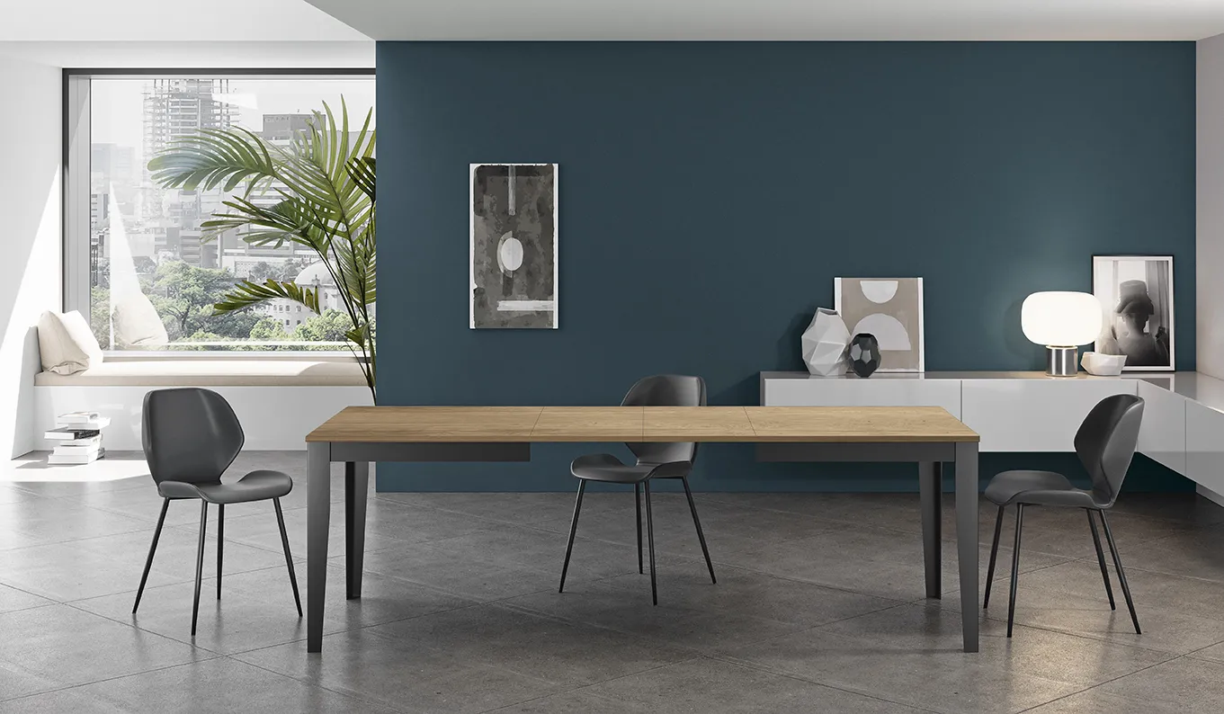 Tavolo Big Stones in rovere con sedie grigie davanti a una parete blu