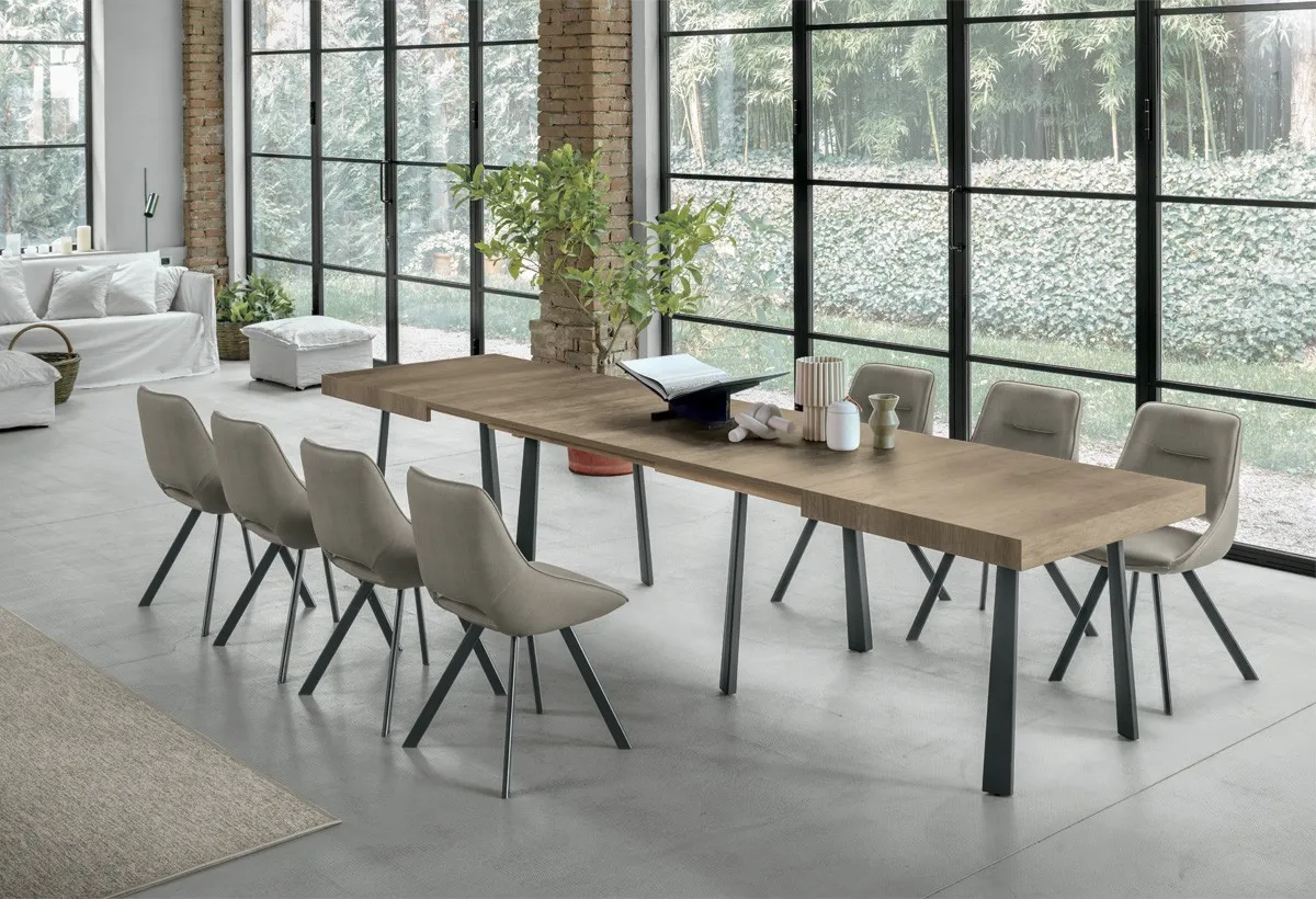 Tavolo Orfeo Target Point con piano effetto legno e struttura grigia, sedie beige in un soggiorno con camino