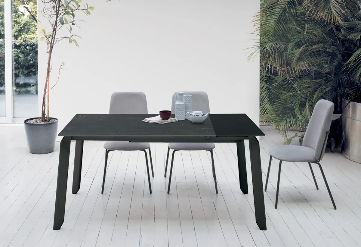 Tavolo Efesto Target Point con piano scuro e gambe sottili nere, sedie grigie