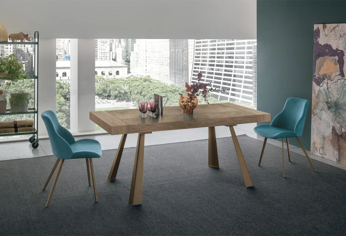 Tavolo Grecale Target Point con piano effetto legno e sedie azzurre davanti a una parete verde