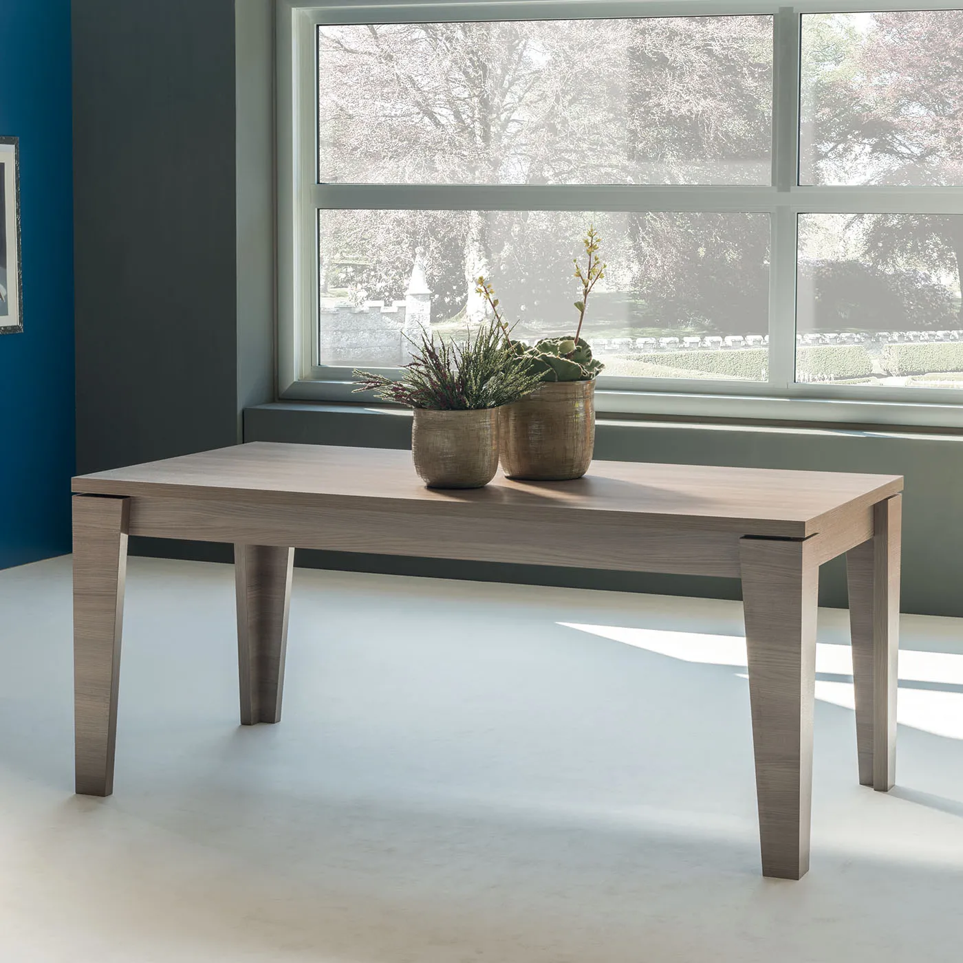 Tavolo Arlen Tecnolegno in finitura legno chiaro davanti a una grande finestra