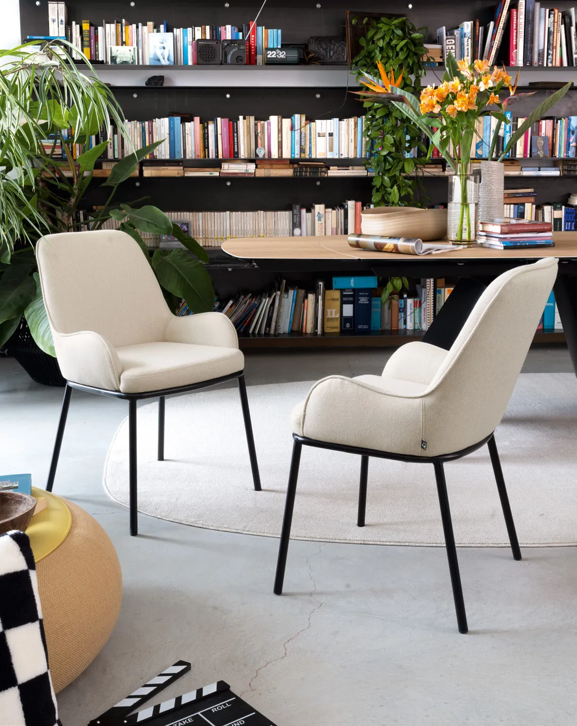 Sedie Flair Connubia in tessuto sabbia con gambe nere accanto a un tavolo e a una grande libreria