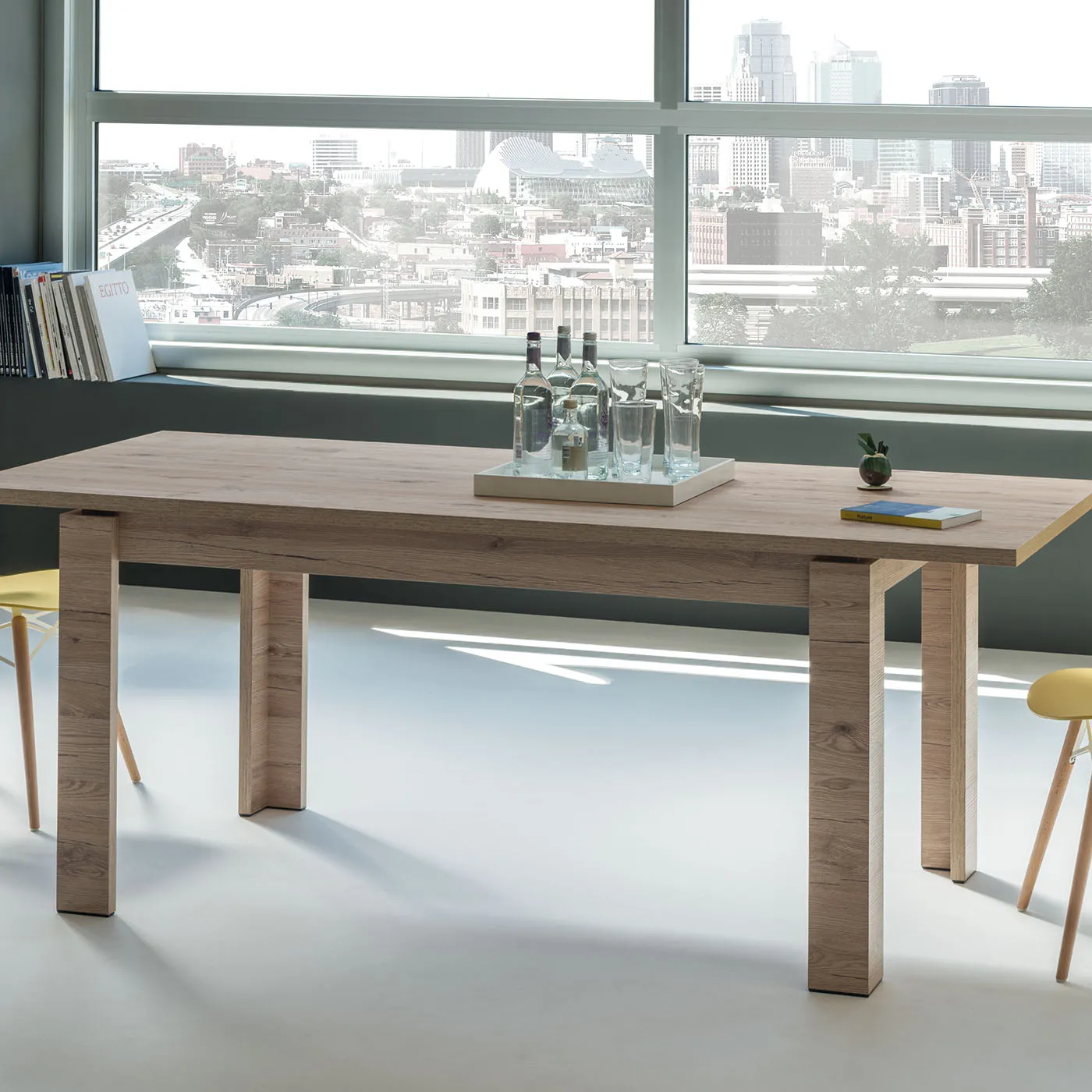 Tavolo Manhattan Tecnolegno effetto rovere davanti a una finestra sulla città