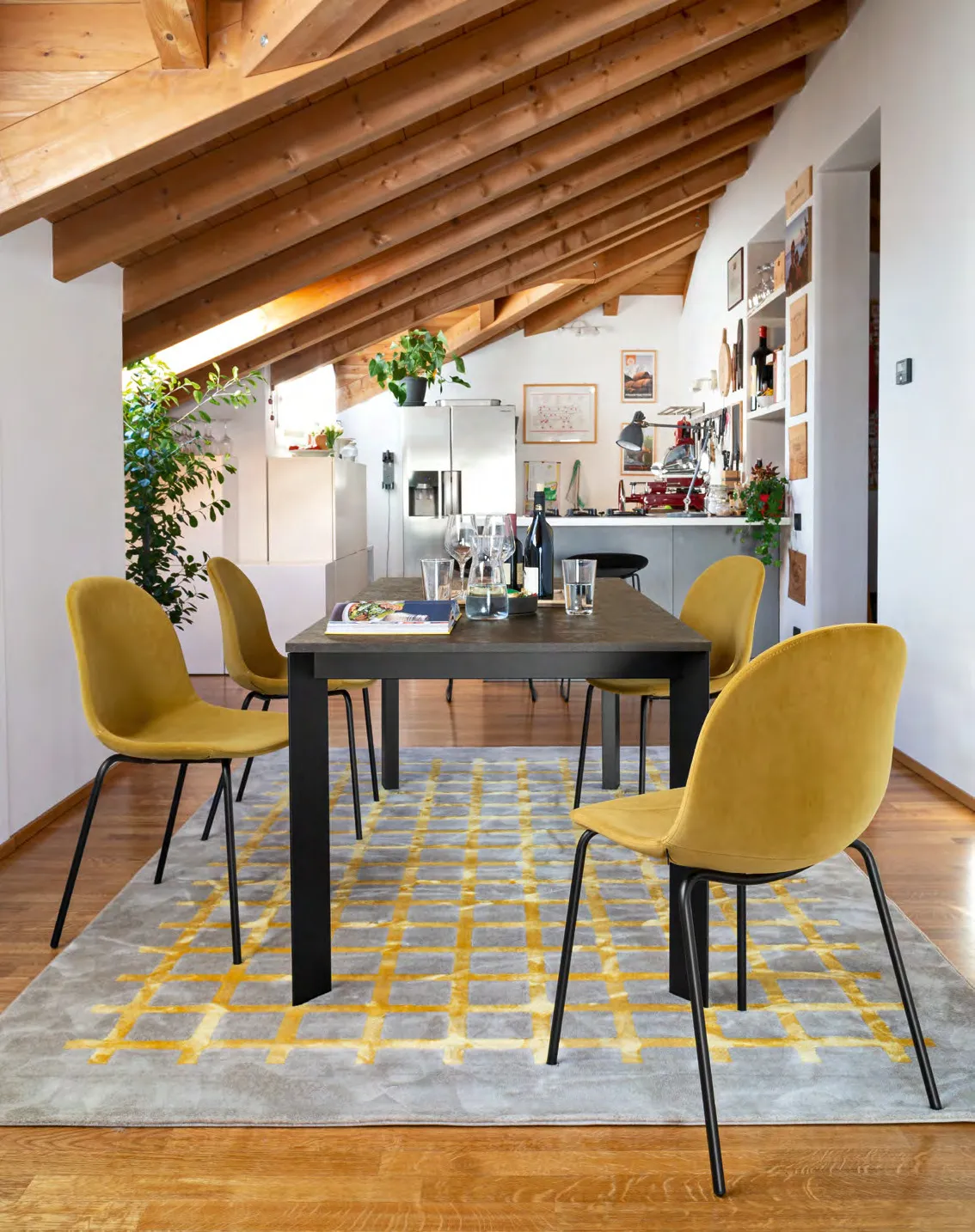 Sedie Academy Connubia in tessuto giallo limone attorno a un tavolo nero sotto un soffitto in legno