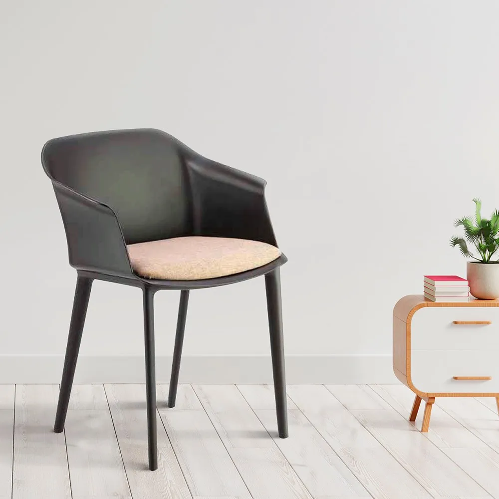 Poltroncina Kona Compir nera con cuscino rosa accanto a un mobiletto