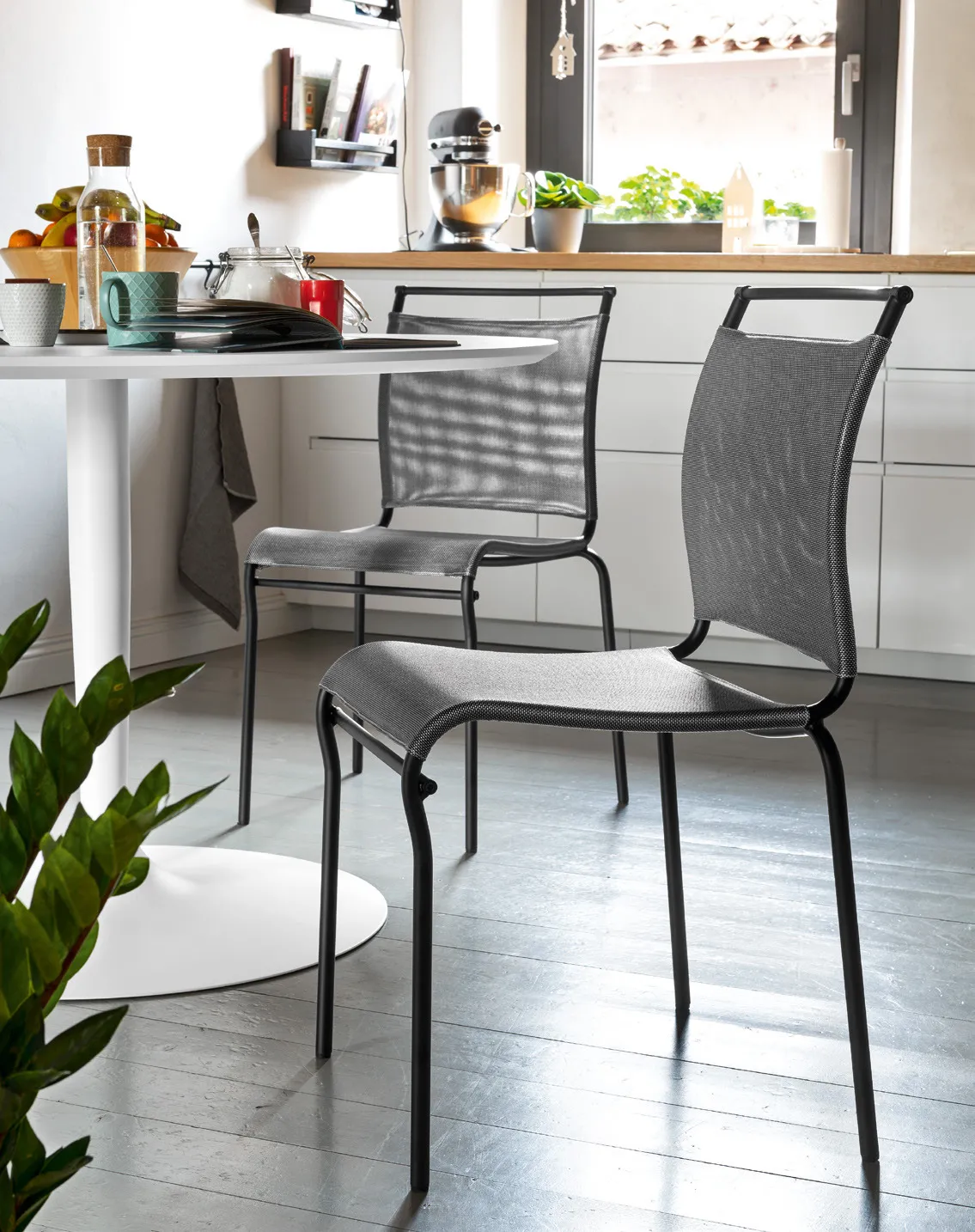 Sedie Air Connubia nere con rete steel attorno a un tavolo rotondo bianco in cucina