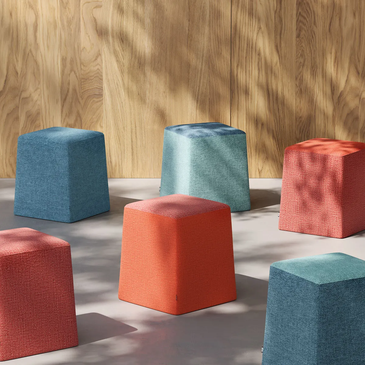 Pouf Stand By Frezza azzurri e arancio davanti a una parete in legno