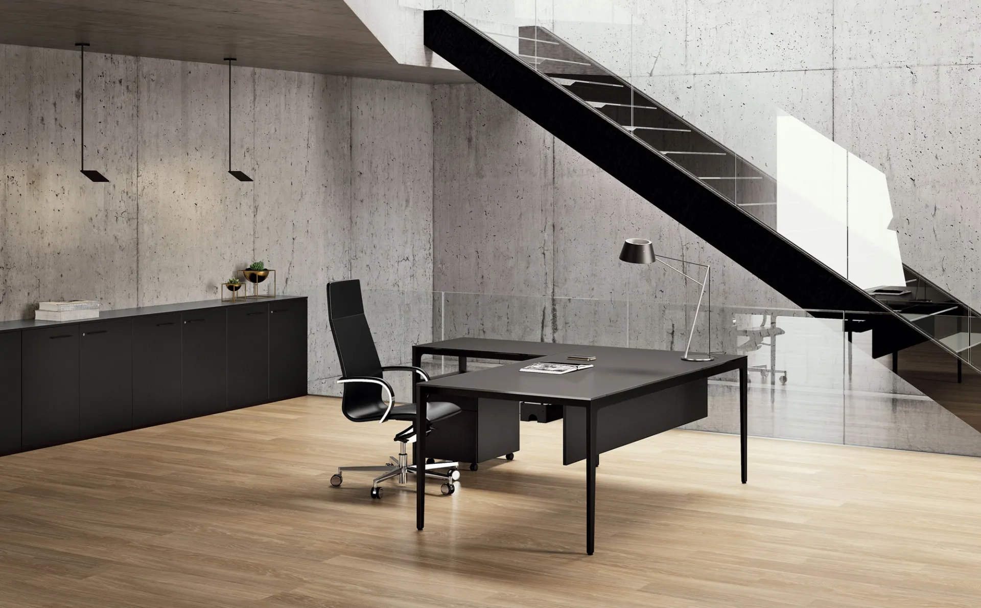 Scrivania Alplus Frezza scura in un ufficio con scala in cemento e parquet