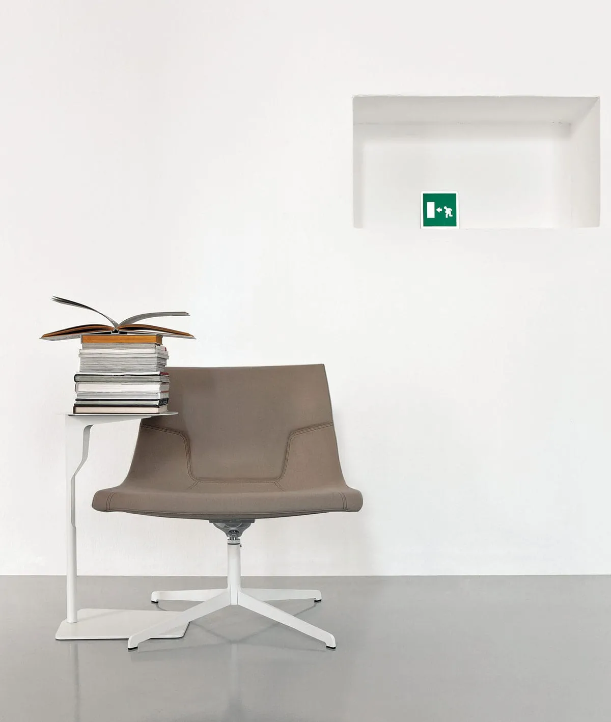 Tavolino Metal Table Frezza bianco con libri accanto a una sedia lounge
