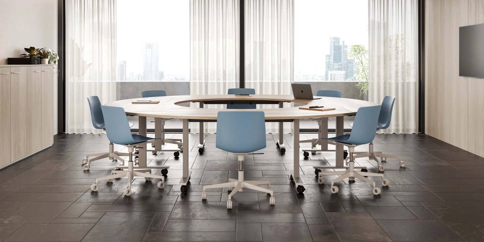 Tavoli Pop Folding Frezza uniti ad anello con sedie azzurre in una sala luminosa