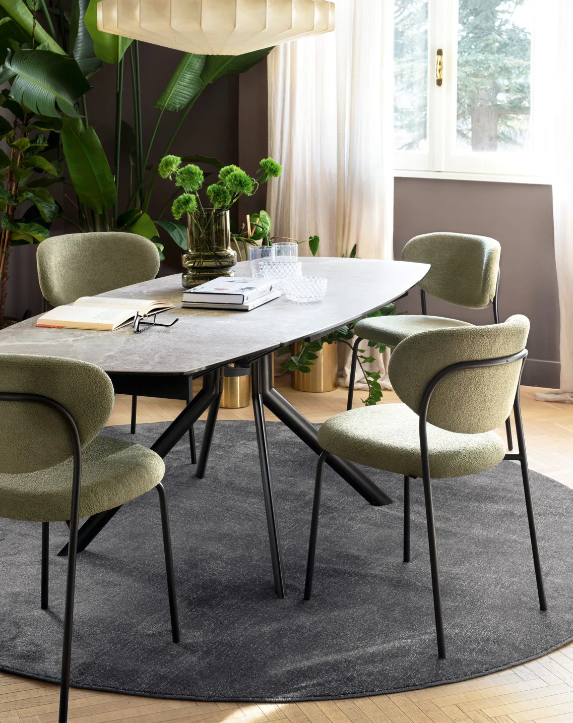 Sedie Cozy Connubia in tessuto salvia con struttura nera attorno a un tavolo in ceramica