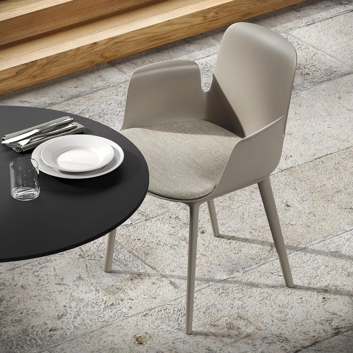 Poltroncina Fior di Loto Plastic Frezza tortora accanto a un tavolo apparecchiato