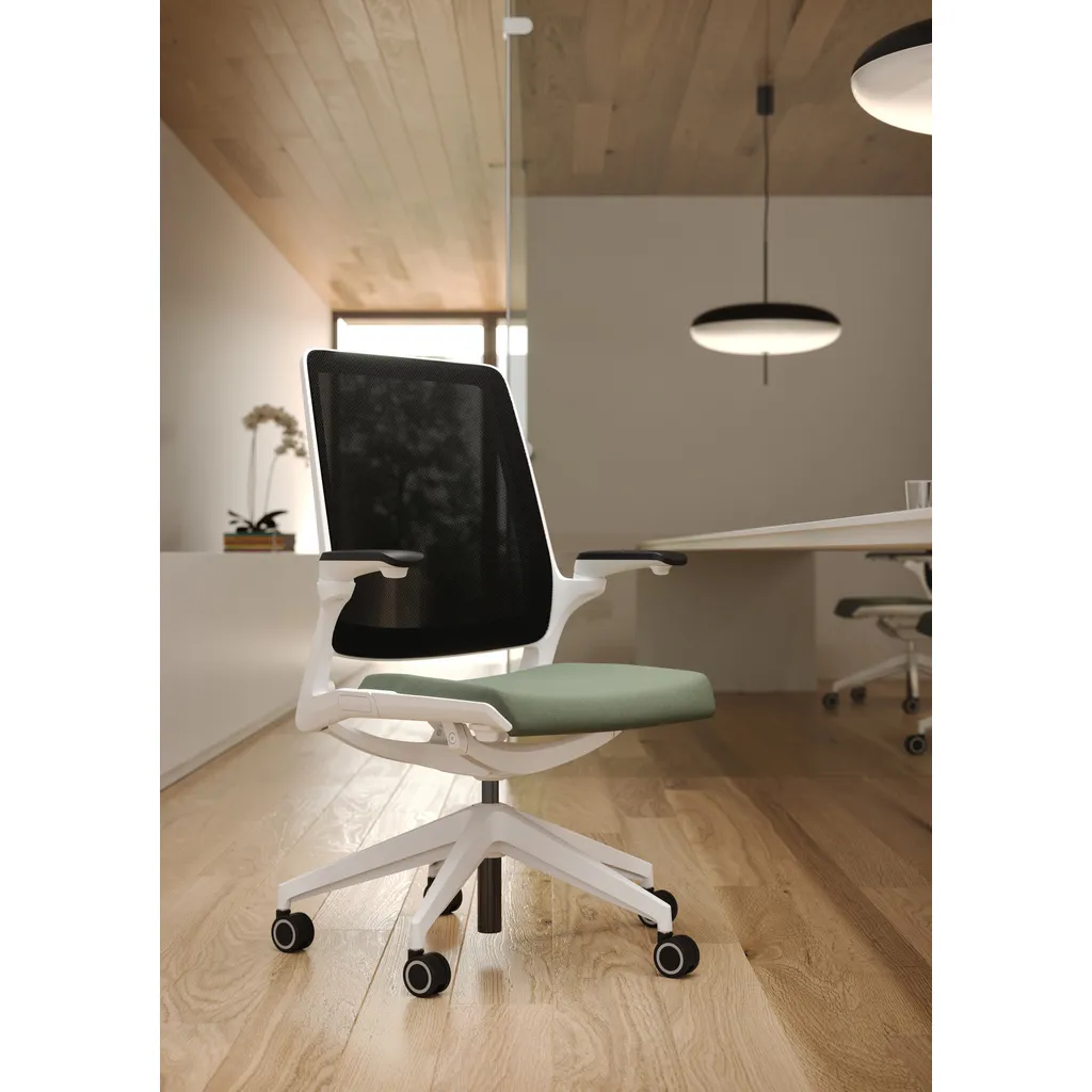 Sedia ergonomica Selfie Elite Unisit bianca con seduta verde in un ufficio in legno