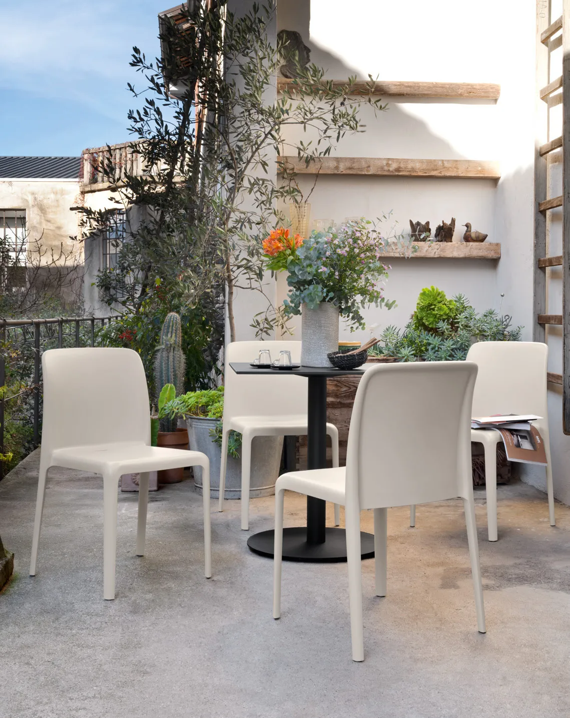 Sedie Bayo Connubia color canapa attorno a un tavolino su una terrazza con piante