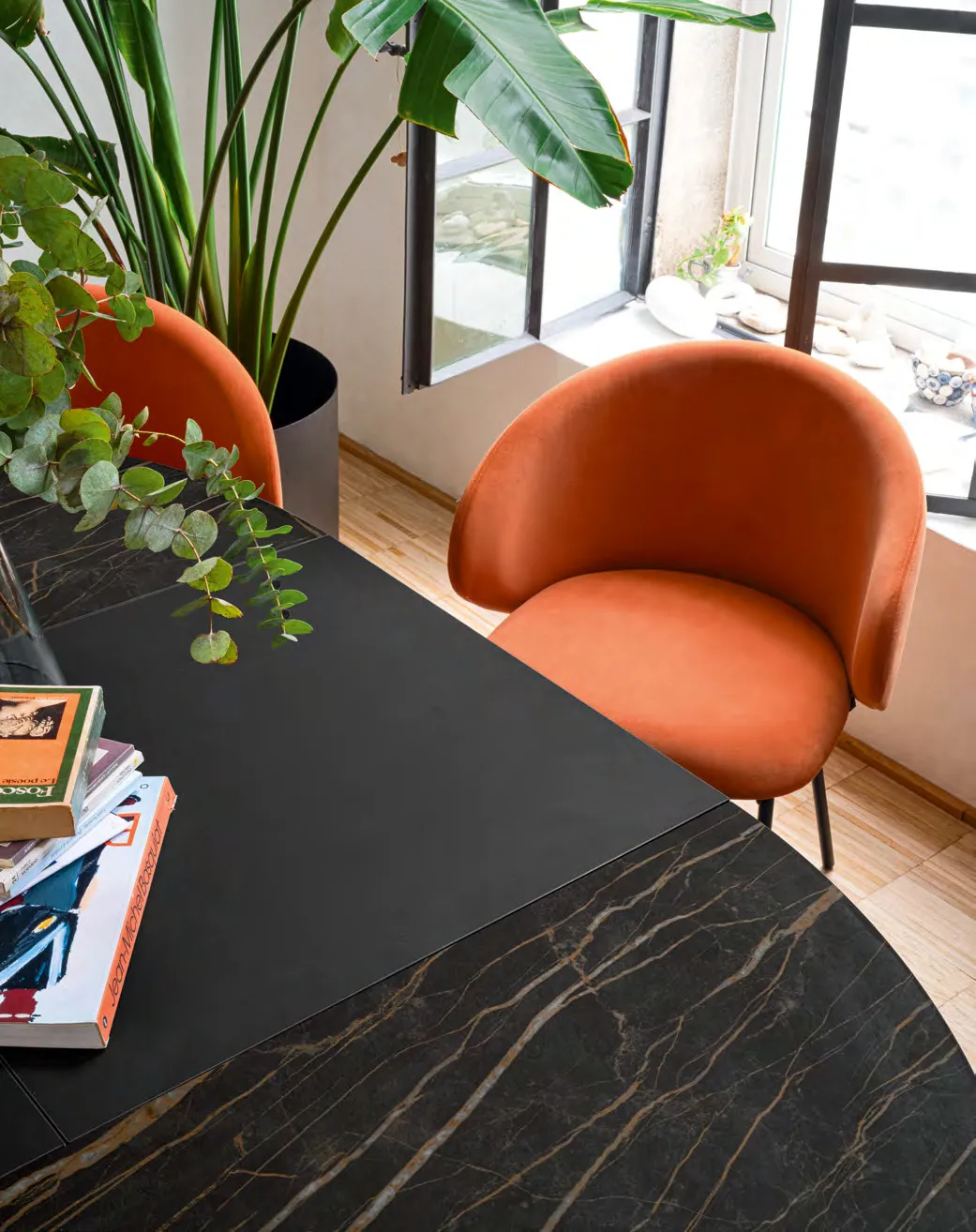 Particolare del bordo del piano in ceramica scura del tavolo Frac Connubia con una sedia arancio