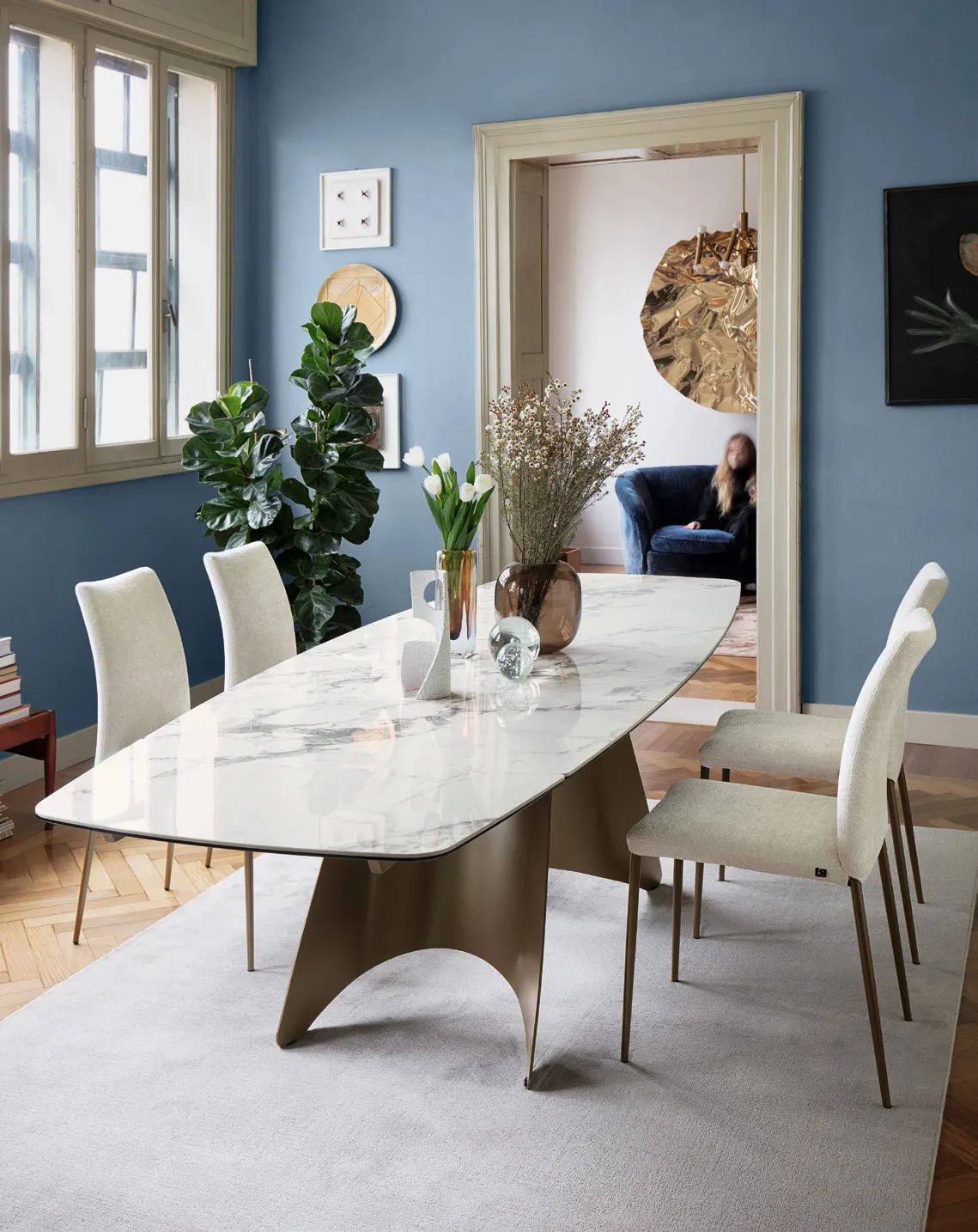 Tavolo Orion Connubia con piano in ceramica marmo bianco e basamento lava in una sala dalle pareti blu