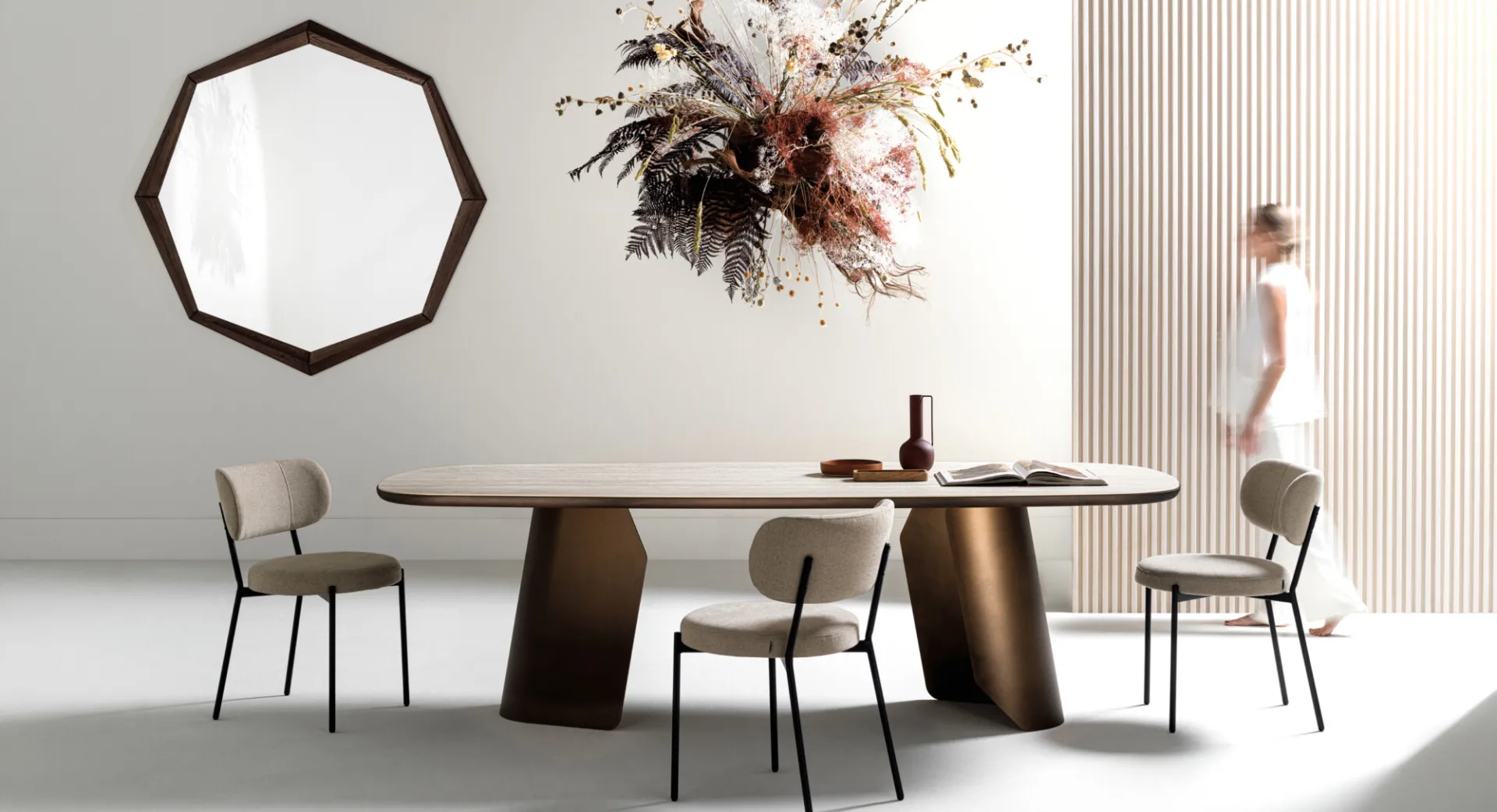 Sedie Mira Devina Nais beige attorno a un tavolo ovale con piano in ceramica e basamento bronzo