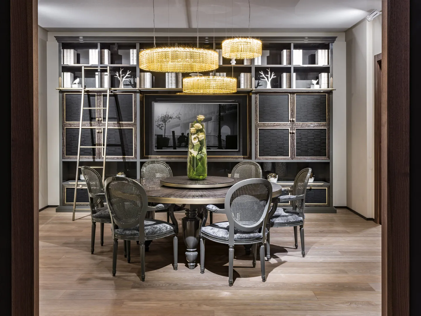 Sala da pranzo Trinity Bernazzoli con parete libreria scura e tavolo rotondo