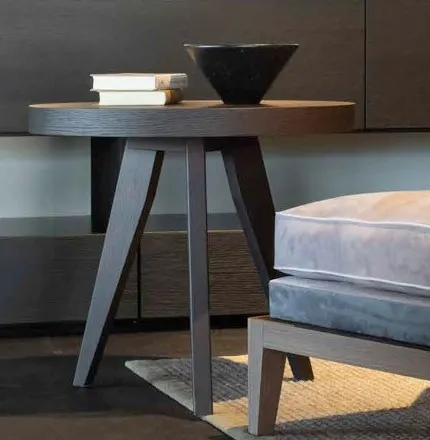 Tavolino tondo Eclipse Bernazzoli in rovere cacao accanto a una poltrona, davanti alla libreria