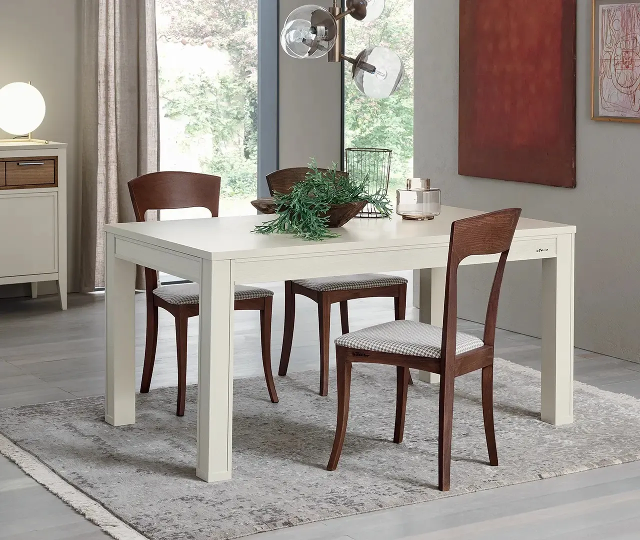 Tavolo Sambuco Le Fablier laccato bianco con sedie in legno scuro su un tappeto chiaro