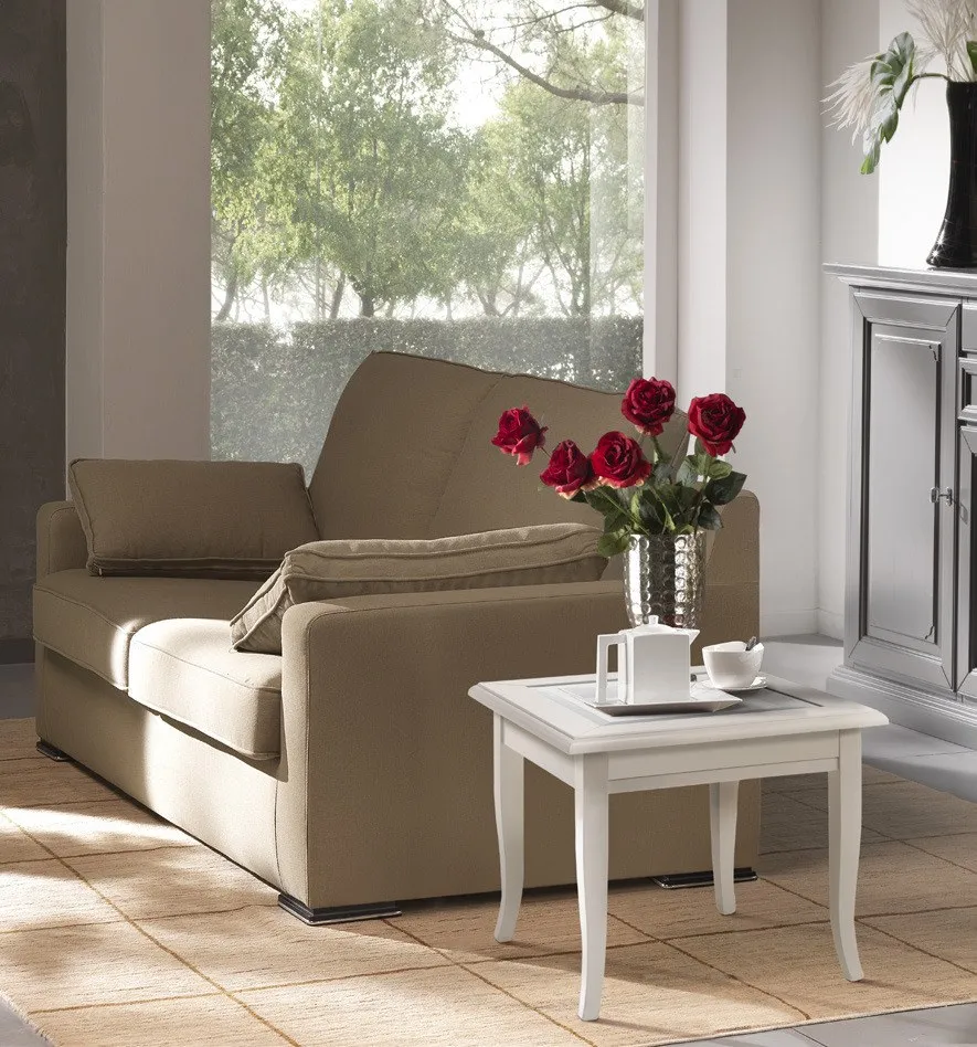 Tavolino quadrato Maison Imba bianco accanto a una poltrona con rose rosse