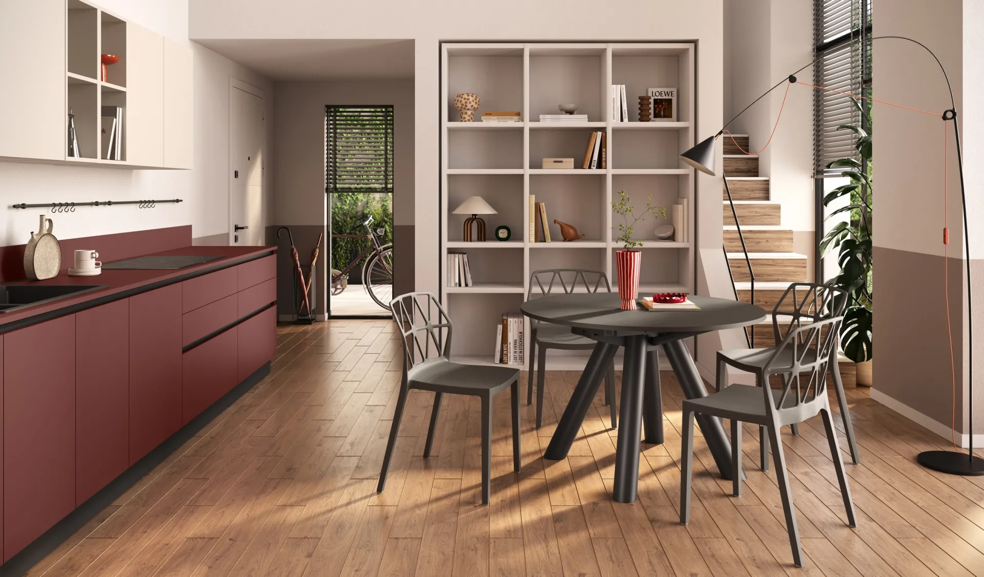 Tavolo Note Scavolini rotondo con gambe divaricate e sedie grigie accanto a una cucina rossa