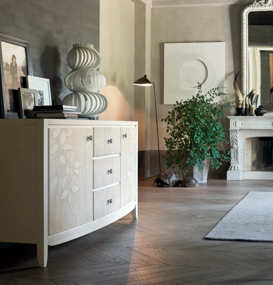 Credenza bombata House Project Imba con decoro a foglie accanto a un camino