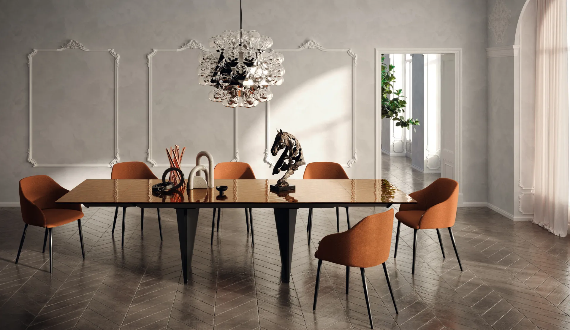 Tavolo Boston Scavolini con piano lucido color bronzo e poltroncine arancioni in una sala con stucchi
