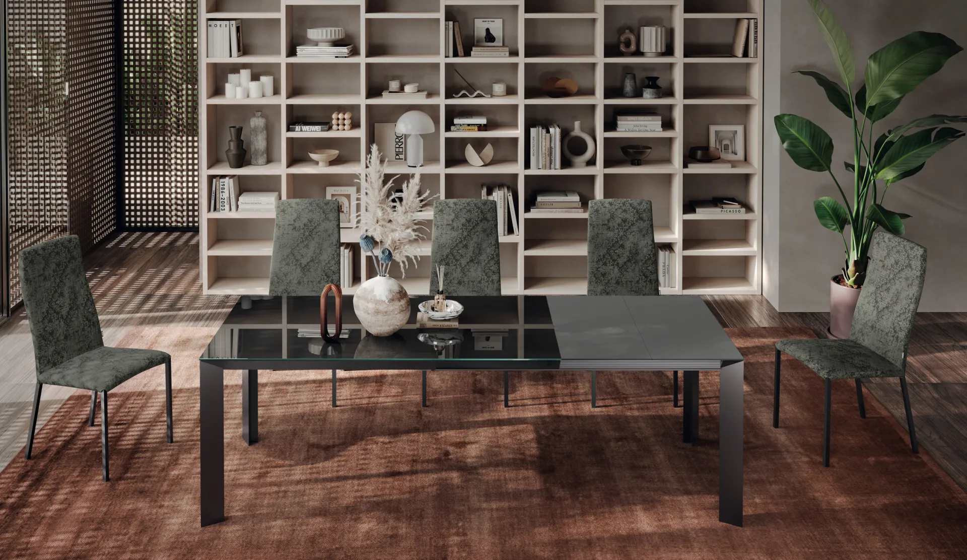 Tavolo Tai Scavolini aperto con piano in vetro scuro e allunga grigia, davanti a una libreria
