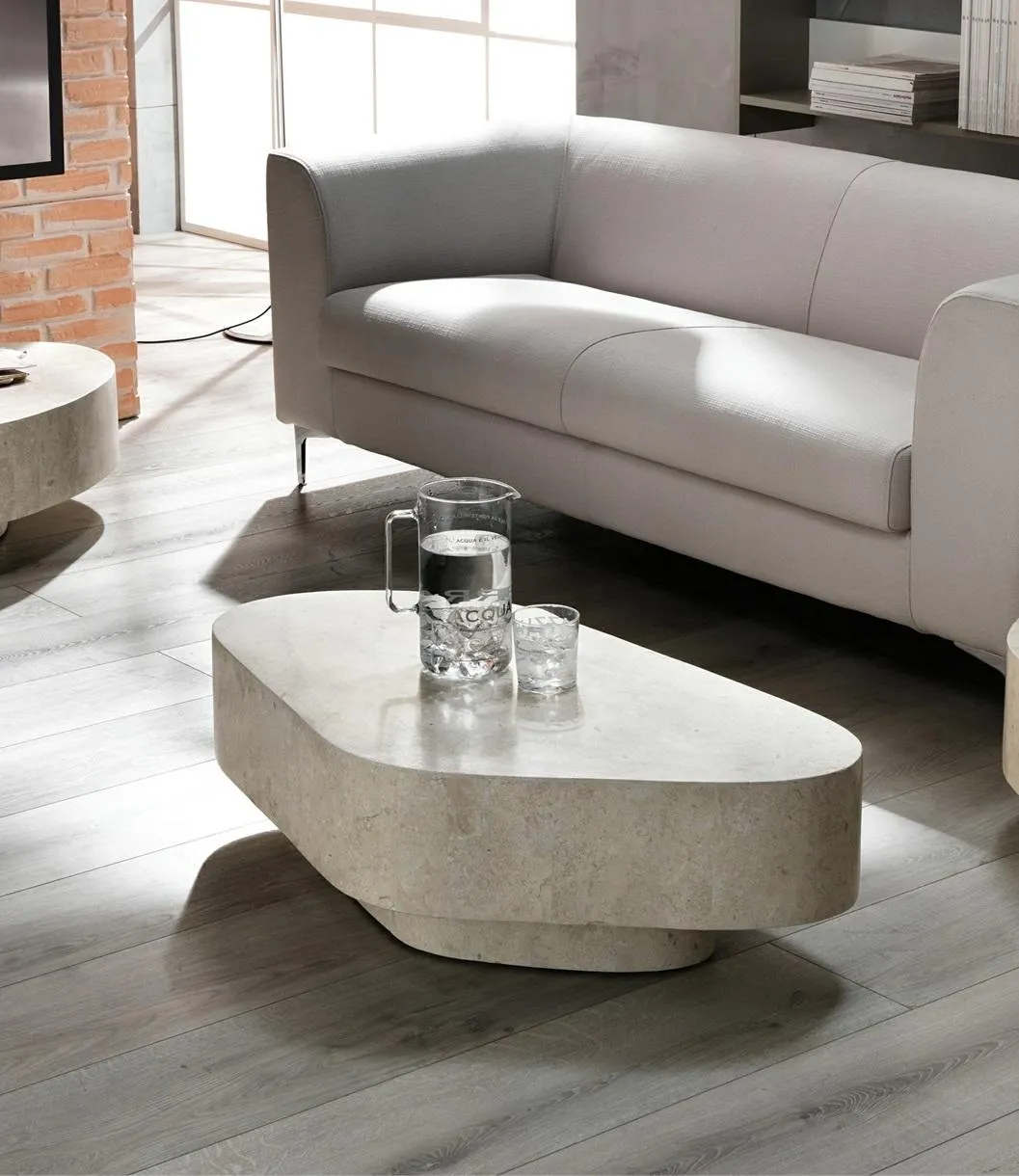 Tavolino Trapezio Stones beige davanti a un divano grigio
